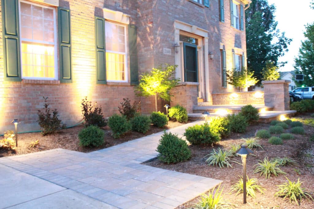 After - A paver landing and walk with columns and fresh plantings make this entrance practical as well as warm and inviting